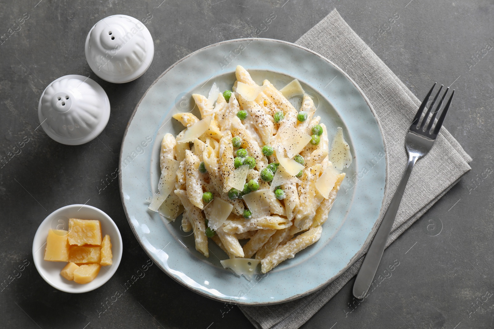 Photo of Delicious pasta with green peas, cheese and creamy sauce on grey table, top view