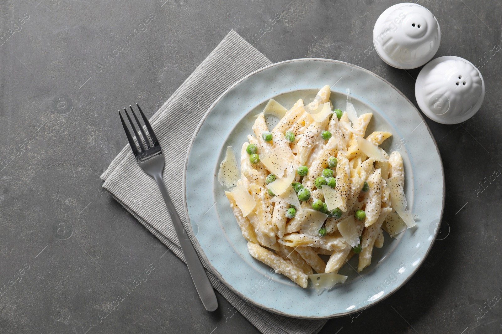 Photo of Delicious pasta with green peas, cheese and creamy sauce on grey table, top view