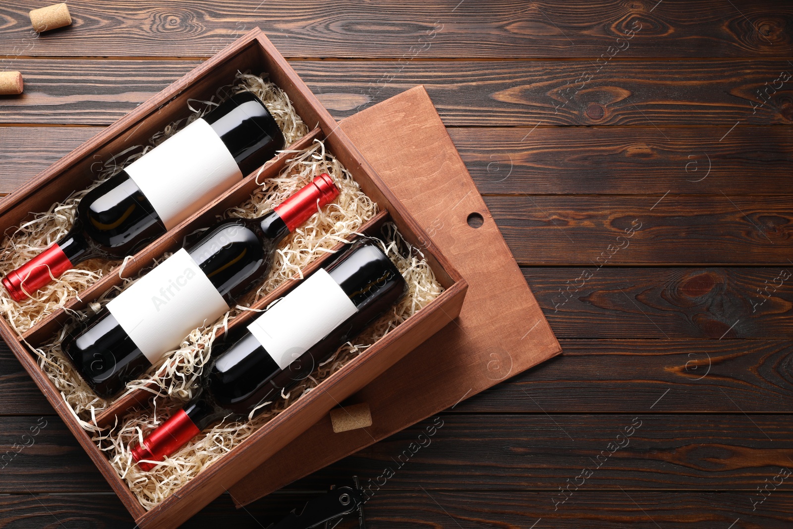 Photo of Box with wine bottles on wooden table, top view. Space for text