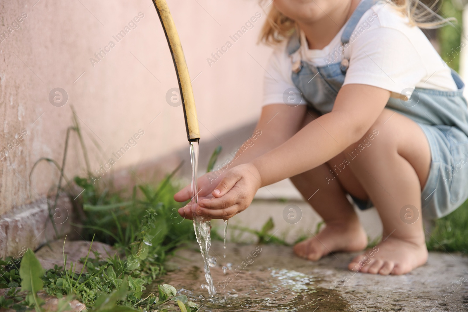 Photo of Water scarcity. Little girl drinking water from tap outdoors, closeup