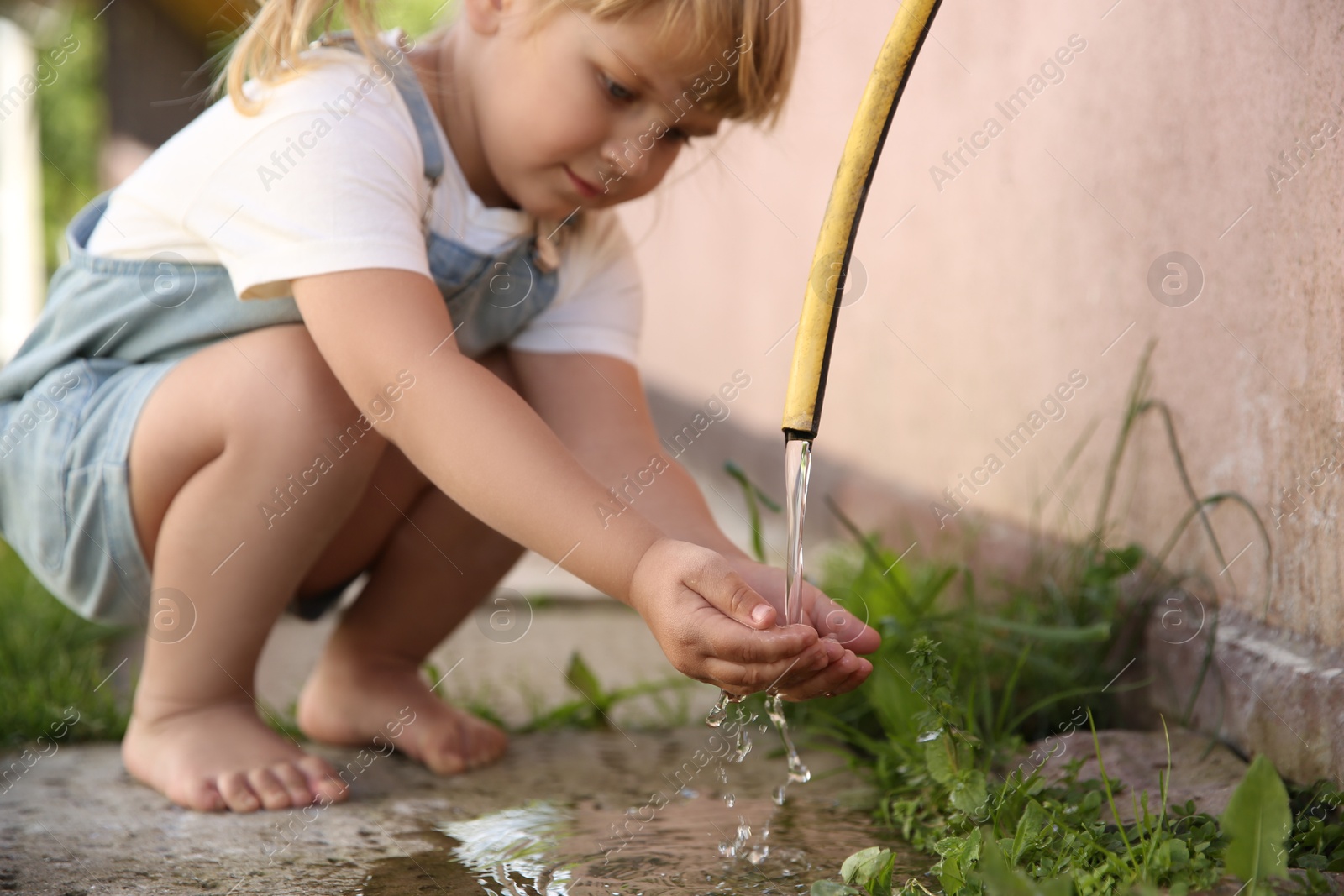 Photo of Water scarcity. Little girl drinking water from tap outdoors, closeup