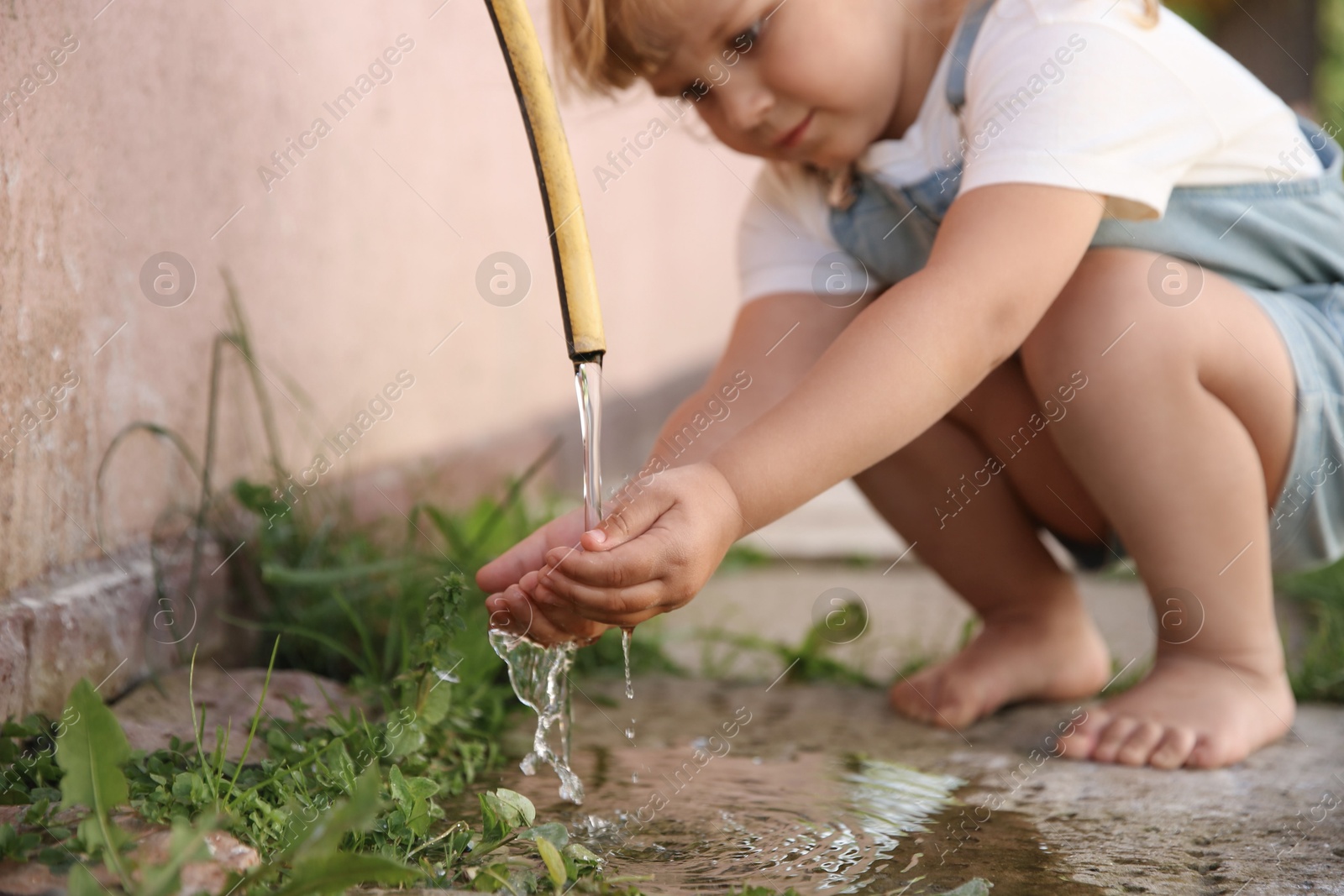 Photo of Water scarcity. Little girl drinking water from tap outdoors, closeup