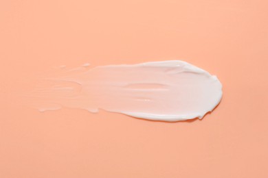 Photo of Sample of face cream on coral background, top view