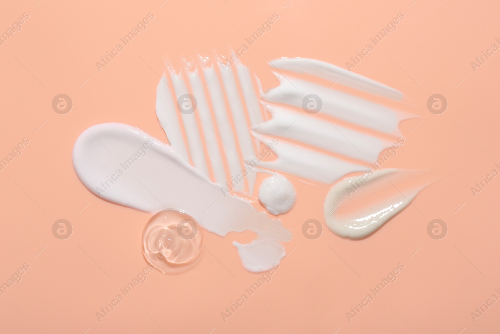 Photo of Samples of face cream on coral background, top view