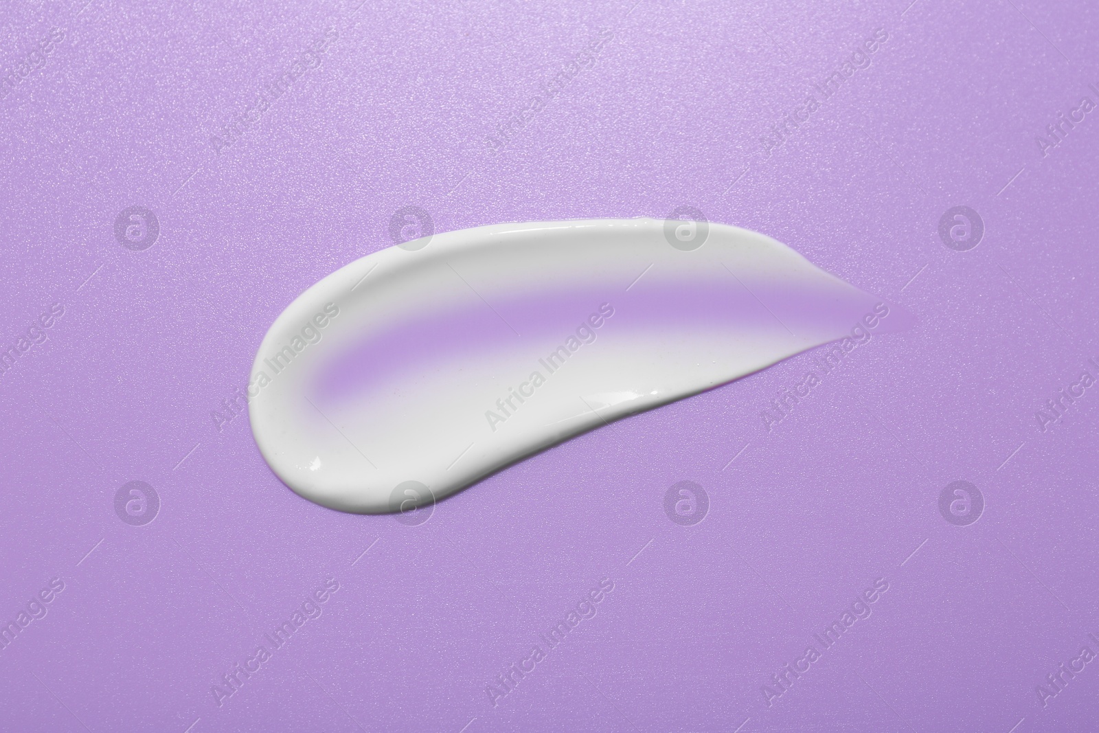 Photo of Sample of face cream on violet background, top view