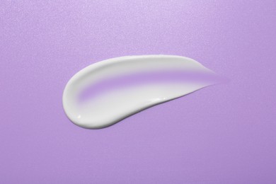 Photo of Sample of face cream on violet background, top view