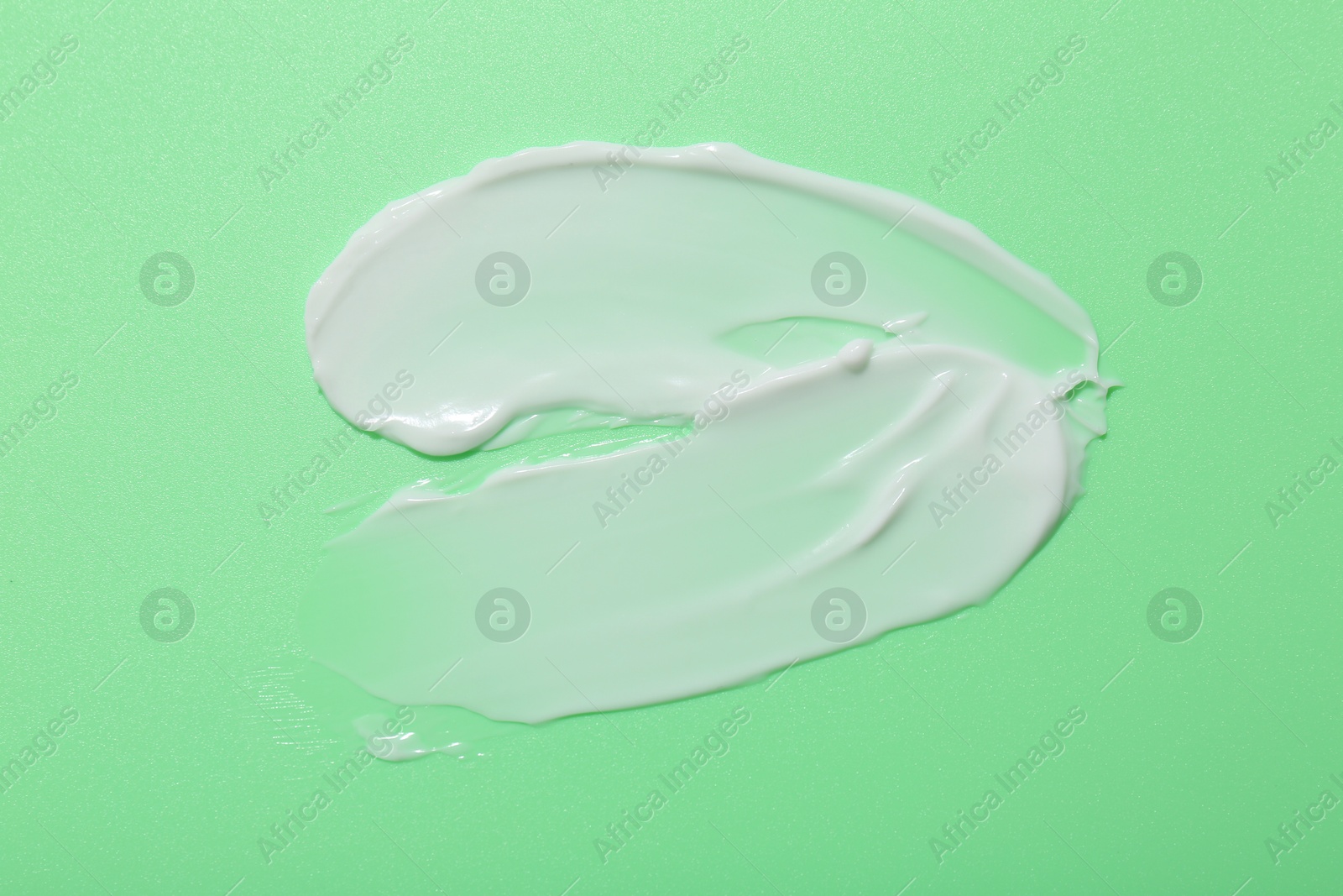 Photo of Samples of face cream on green background, top view