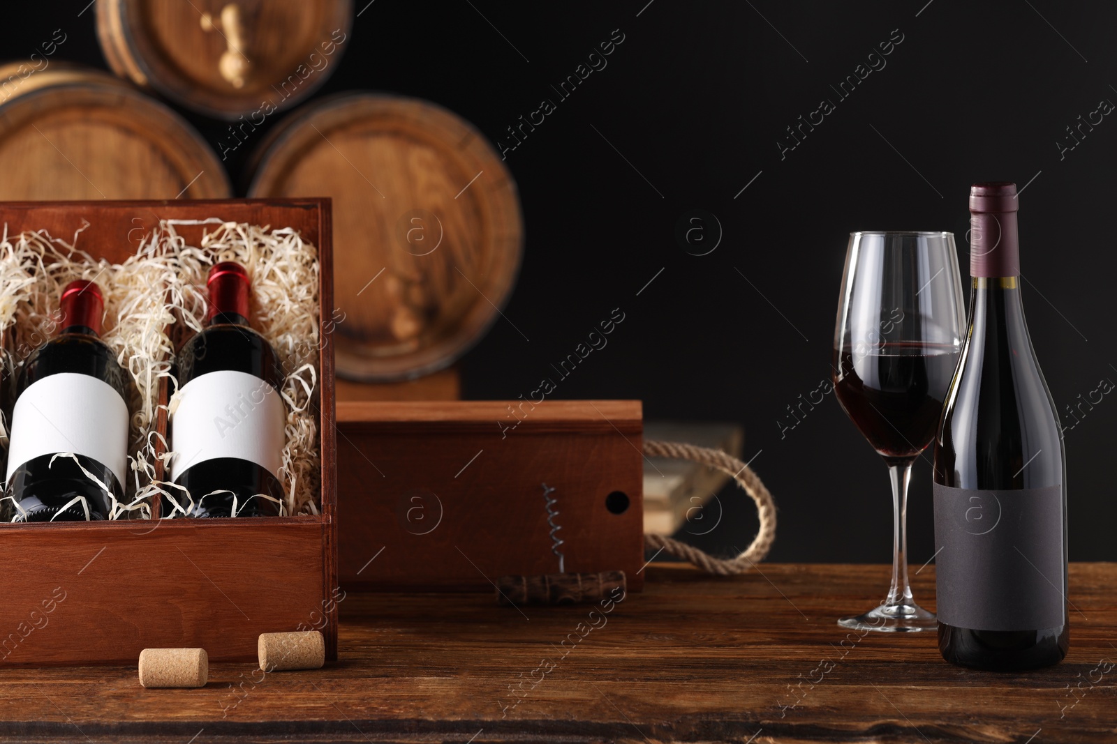 Photo of Wooden boxes, glass and wine bottles on table against dark background