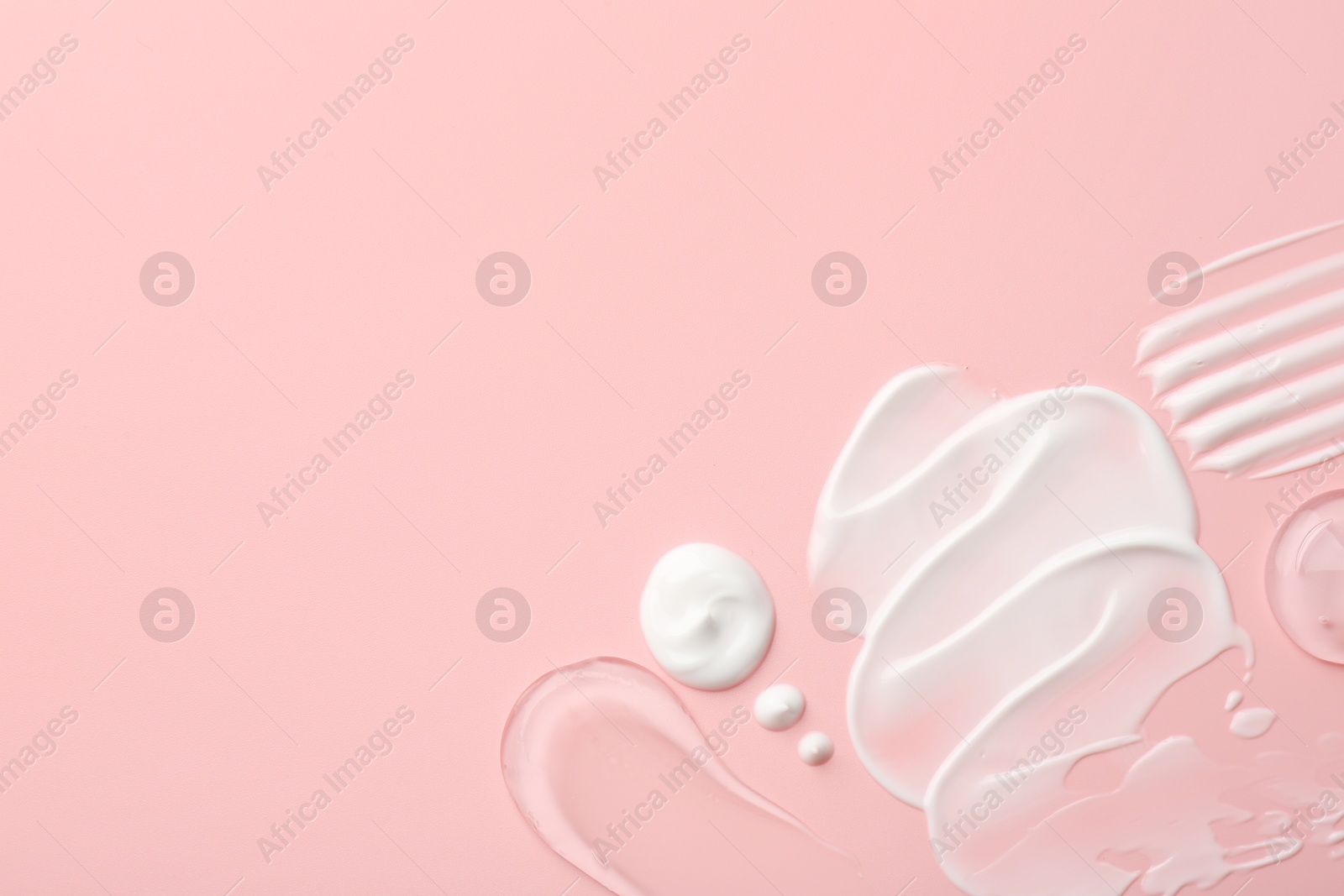 Photo of Samples of face cream on pink background, top view. Space for text