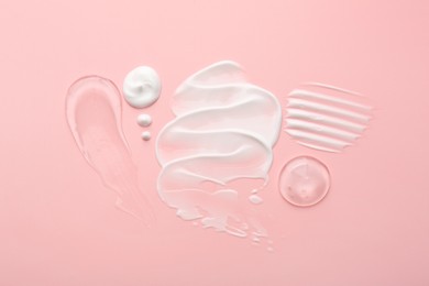 Photo of Samples of face cream on pink background, flat lay