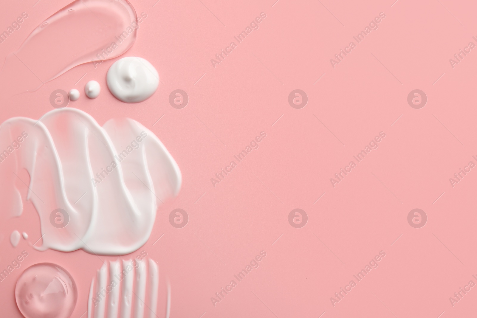 Photo of Samples of face cream on pink background, top view. Space for text