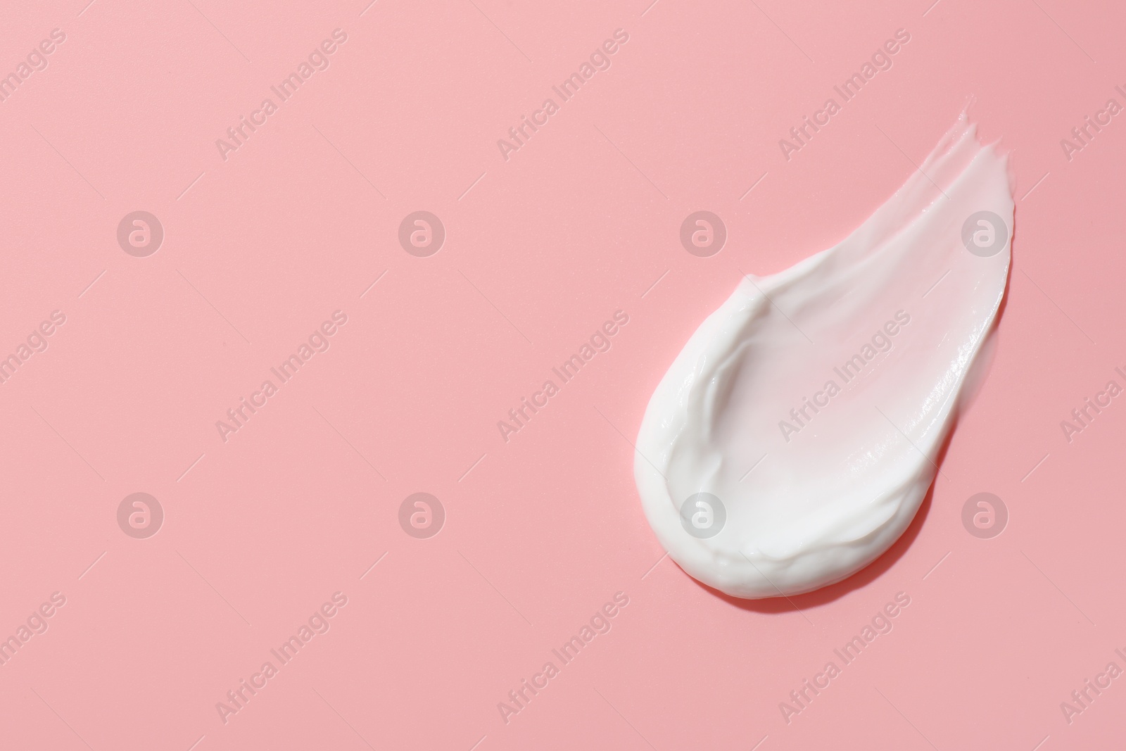 Photo of Sample of face cream on pink background, top view. Space for text