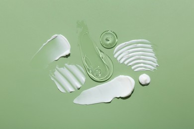 Photo of Samples of face cream on green background, top view