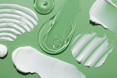 Photo of Samples of face cream on green background, top view