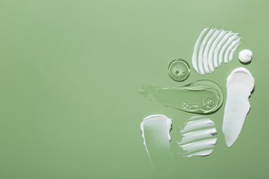 Samples of face cream on green background, top view. Space for text