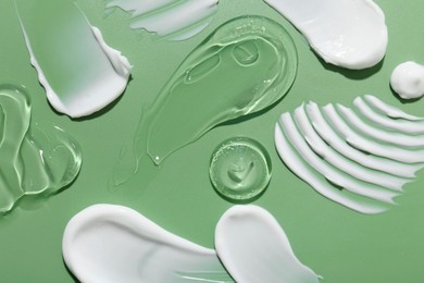 Photo of Samples of face cream on green background, top view