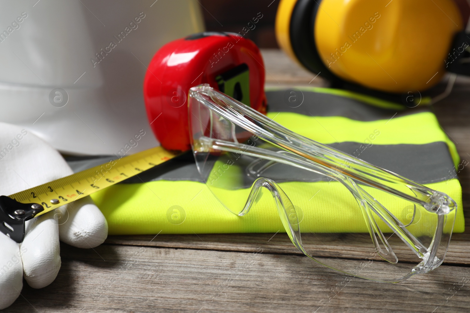 Photo of Goggles and other personal protective equipment on wooden surface, closeup