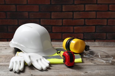 Photo of White hard hat and other personal protective equipment on wooden surface