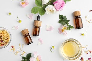 Photo of Aromatherapy. Essential oils, flowers and petals on white background, flat lay