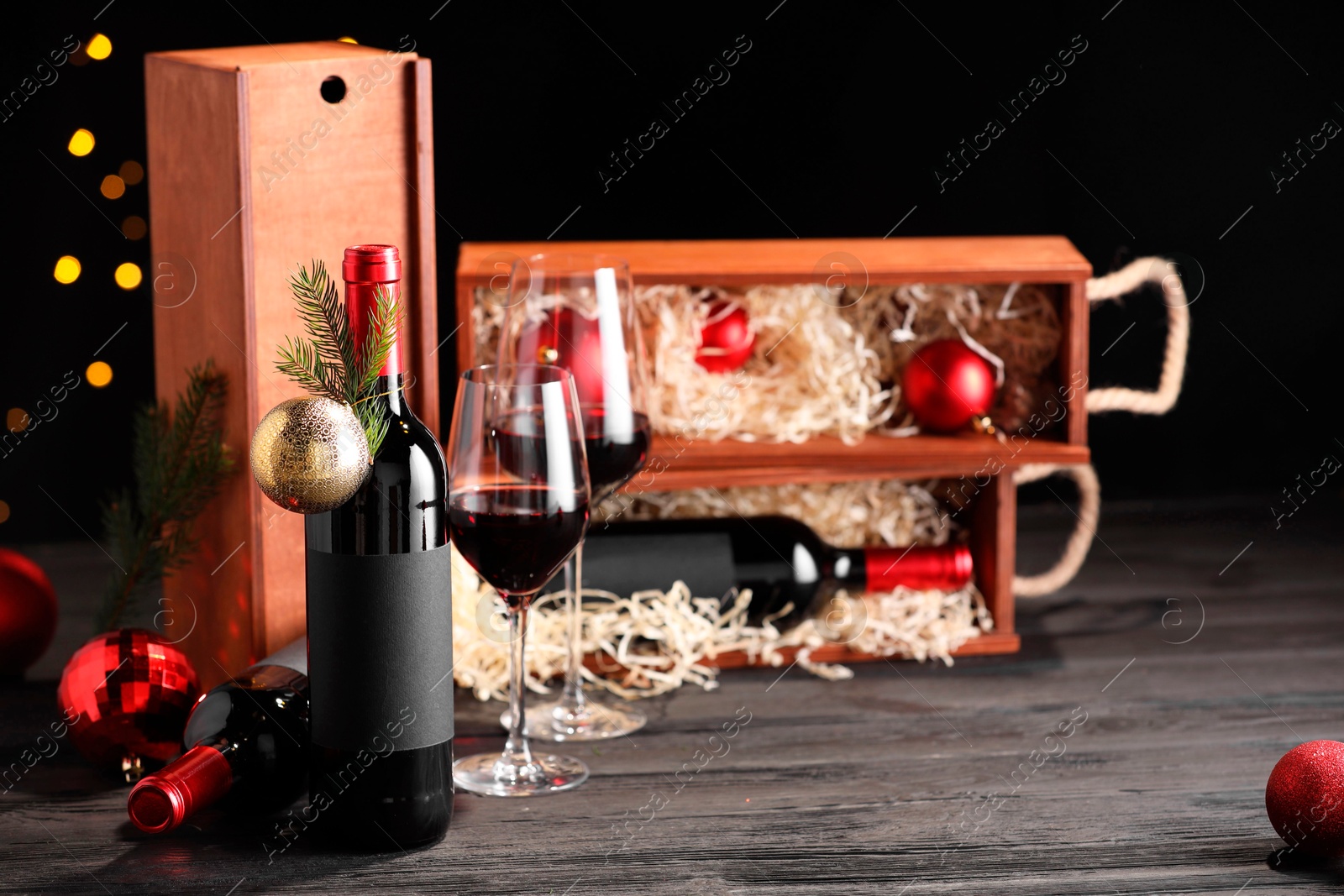 Photo of Bottles of wine, glasses, wooden boxes, fir twigs and Christmas balls on table