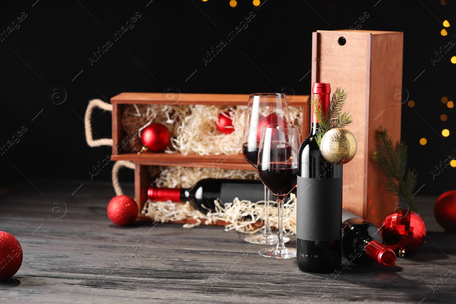 Photo of Bottles of wine, glasses, wooden boxes, fir twigs and Christmas balls on table