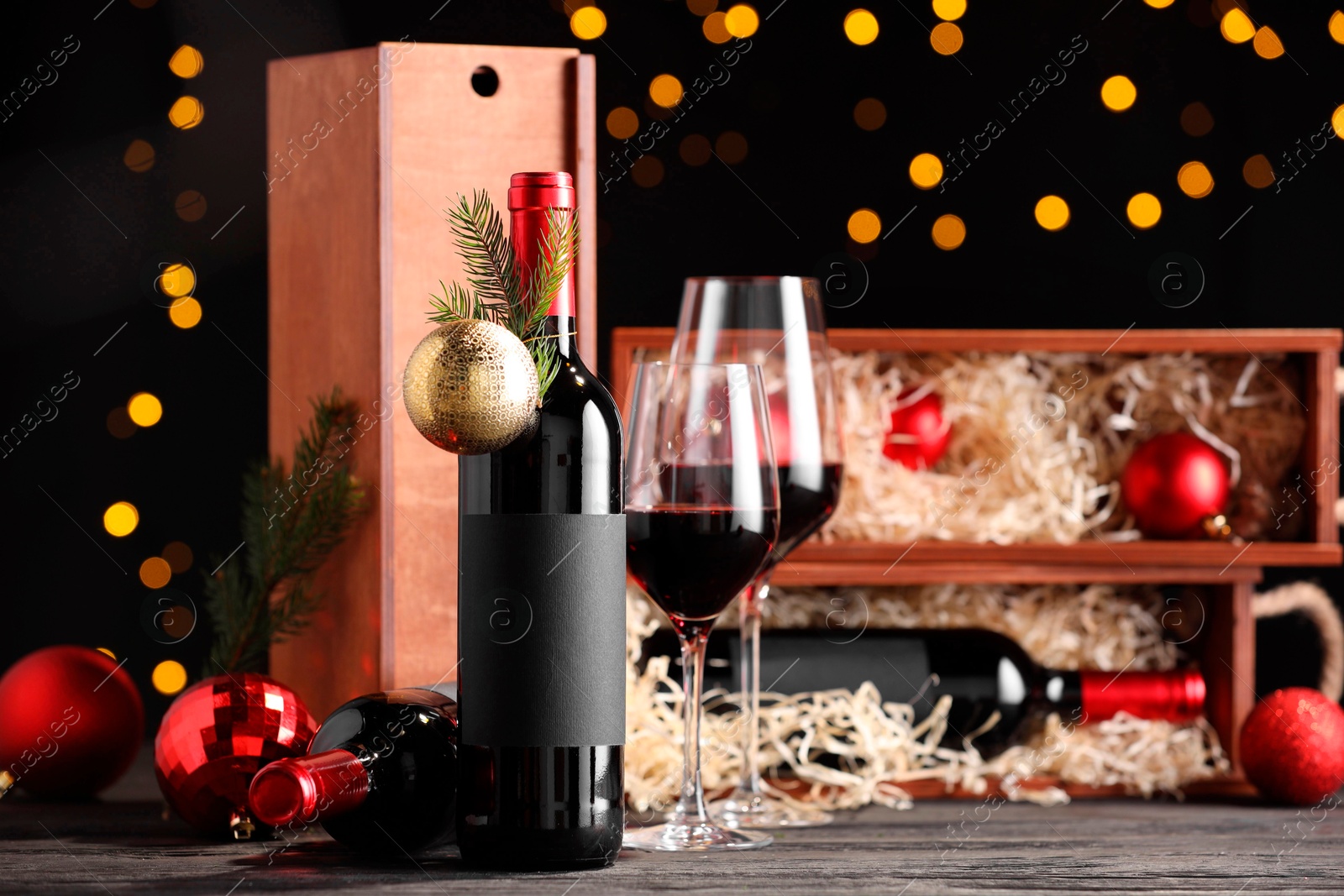 Photo of Bottles of wine, glasses, wooden boxes, fir twigs and Christmas balls on table