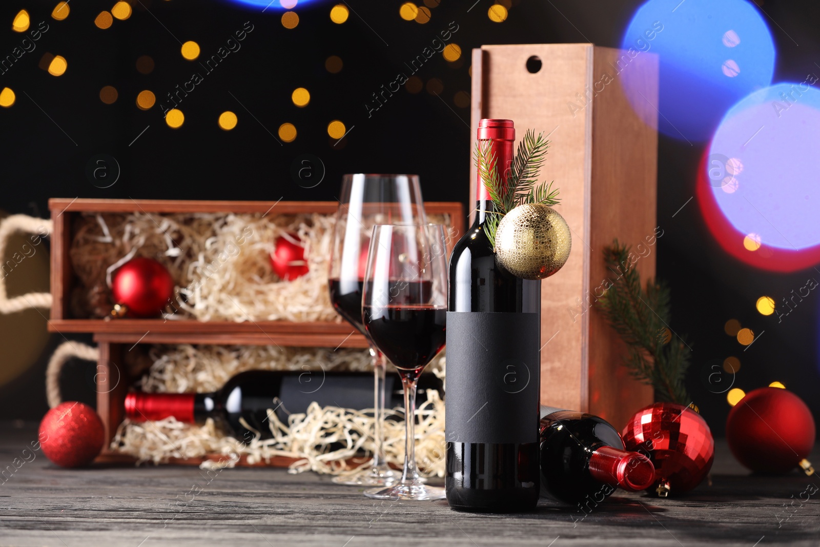 Photo of Bottles of wine, glasses, wooden boxes, fir twigs and Christmas balls on table