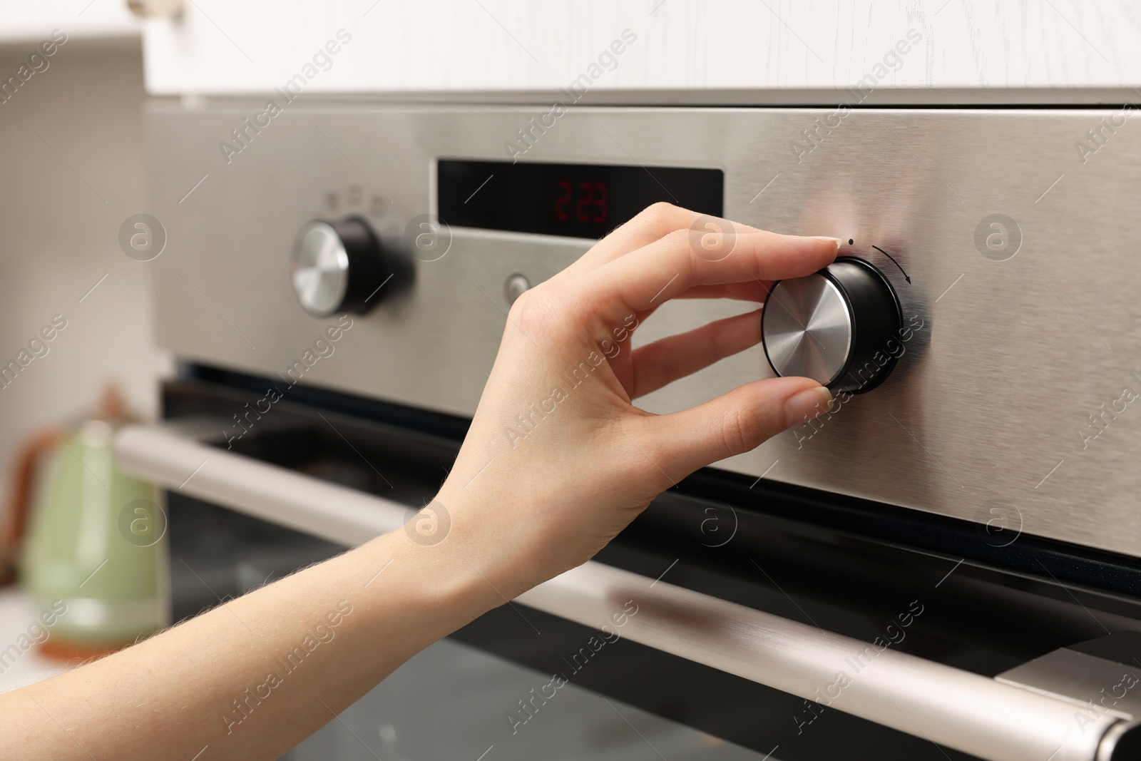 Photo of Woman using electric oven in kitchen, closeup