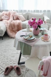 Photo of Beautiful table setting with pink peonies in living room