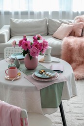 Photo of Beautiful table setting with pink peonies in living room