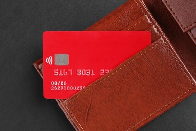 Photo of Credit card in leather wallet on black background, top view