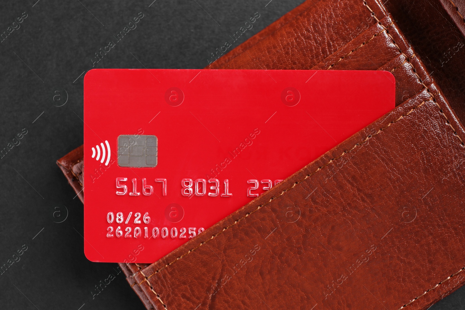 Photo of Credit card in leather wallet on black background, top view