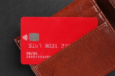 Photo of Credit card in leather wallet on black background, top view