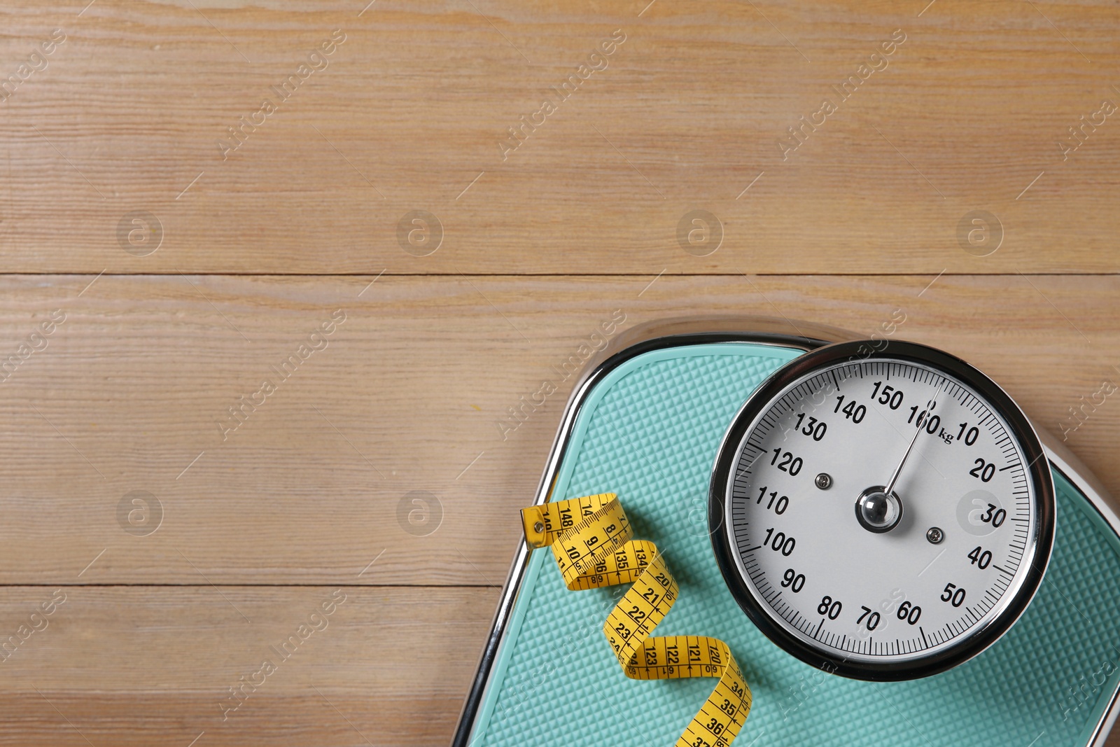 Photo of Scale and measuring tape on wooden floor, top view. Space for text