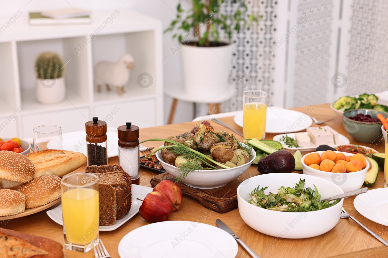 Photo of Healthy vegetarian food, glasses of juice, cutlery and plates on wooden table indoors