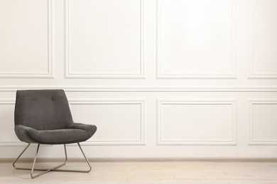 Photo of Soft armchair in light room. Space for text