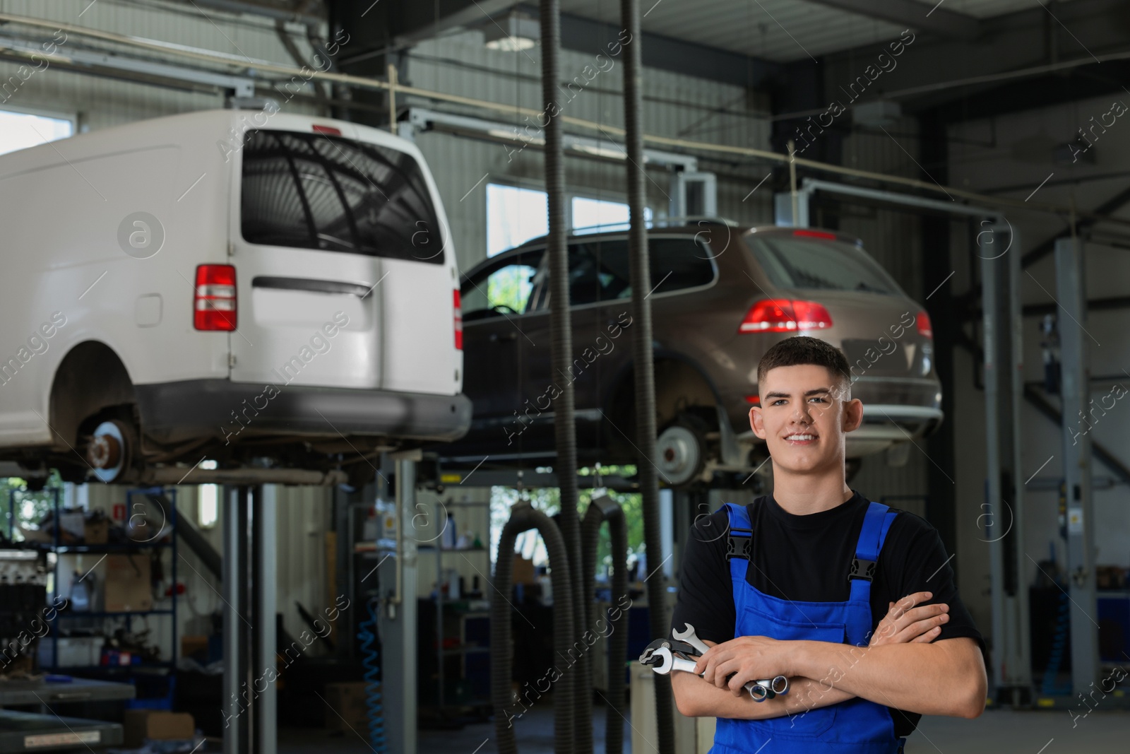 Photo of Young auto mechanic with wrenches at automobile repair shop