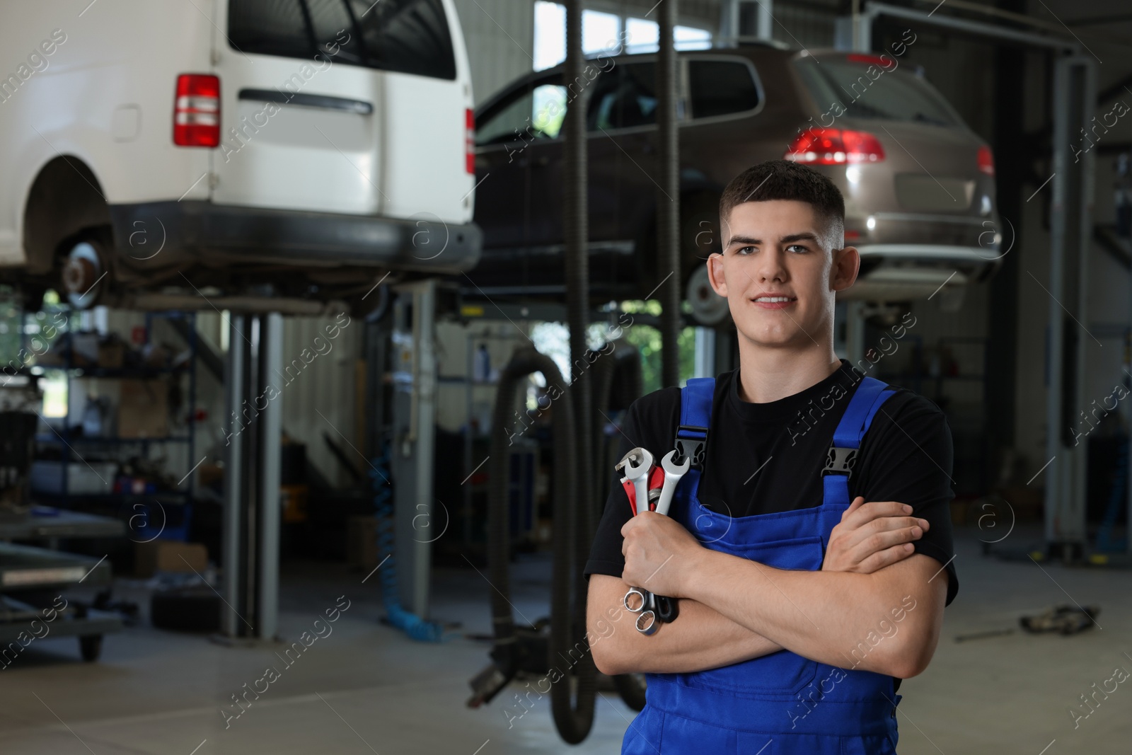 Photo of Young auto mechanic with wrenches at automobile repair shop