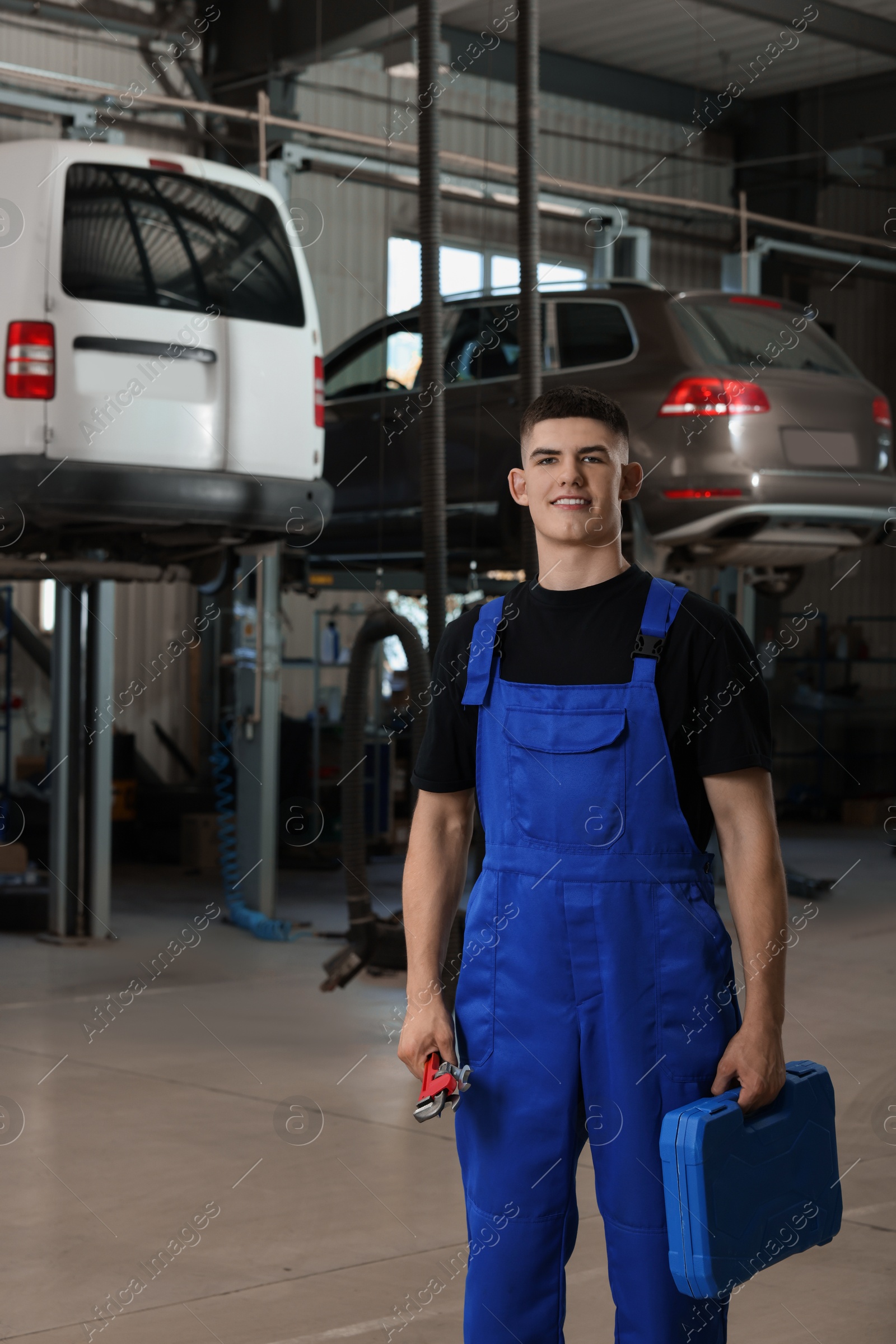 Photo of Young auto mechanic with different tools at automobile repair shop