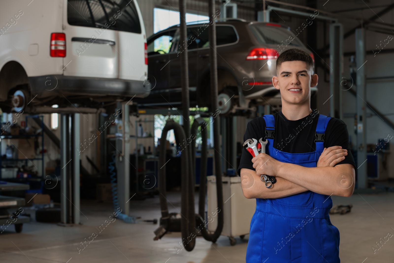 Photo of Young auto mechanic with wrenches at automobile repair shop