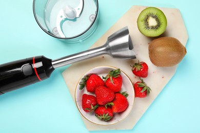 Hand blender kit and fresh fruits on light blue background, top view