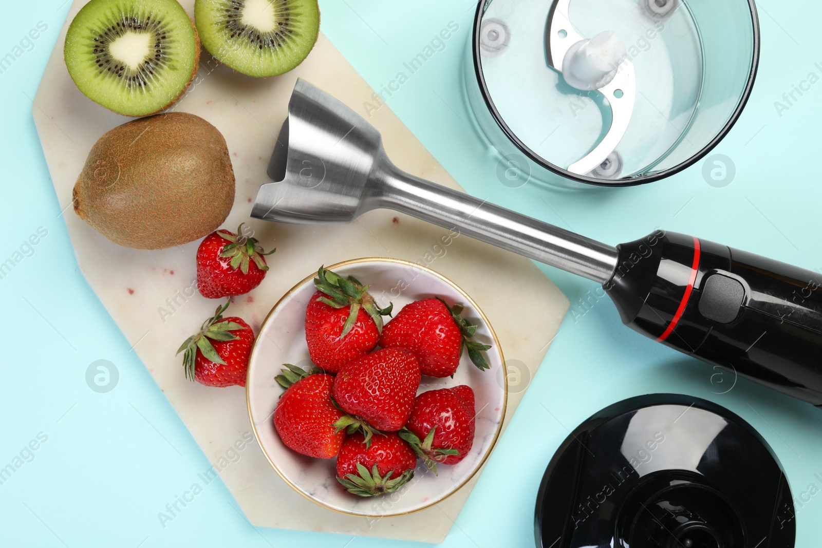 Photo of Hand blender kit and fresh fruits on light blue background, top view