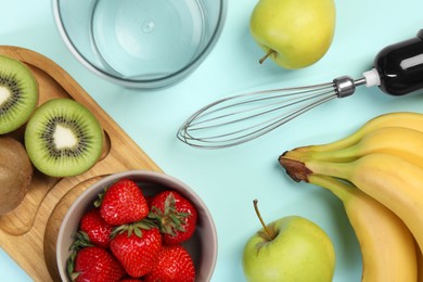 Photo of Hand blender kit and fresh fruits on light blue background, flat lay