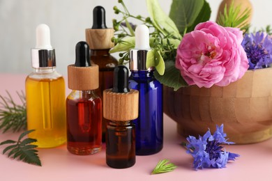 Photo of Aromatherapy. Different essential oils and flowers on pink table