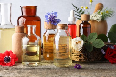 Photo of Aromatherapy. Different essential oils, flowers and green leaves on wooden table