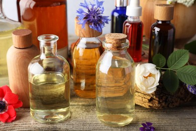 Photo of Aromatherapy. Different essential oils, flowers and green leaves on wooden table