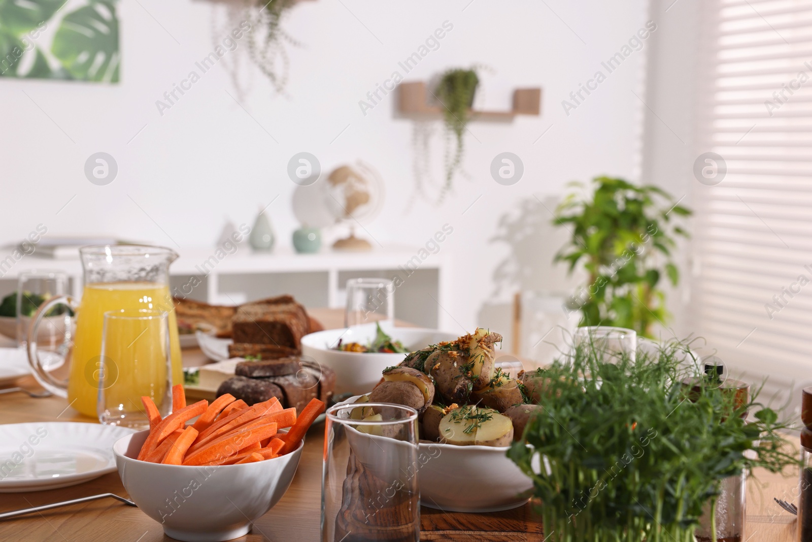 Photo of Healthy vegetarian food, jug of juice and glasses on table indoors