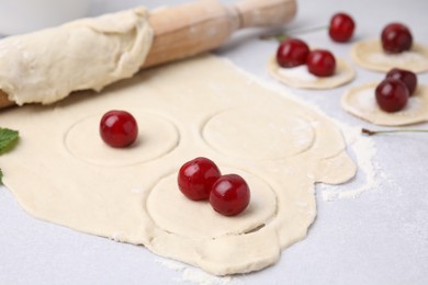 Photo of Process of making dumplings (varenyky) with cherries. Raw dough and ingredients on light table