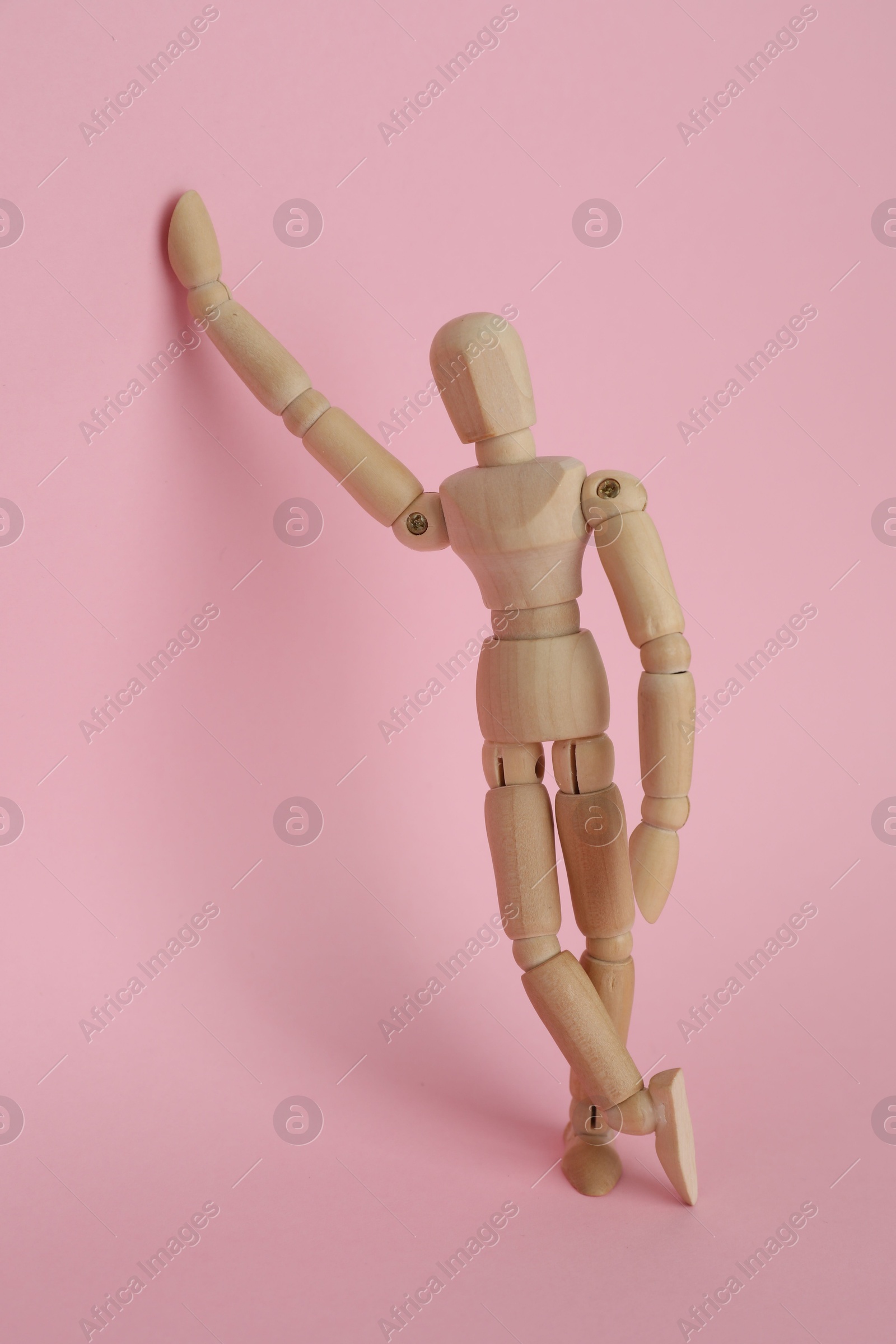 Photo of Wooden human model on pink background. Mini mannequin