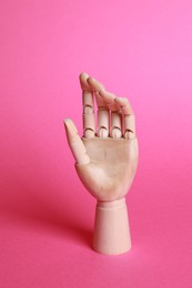 Photo of Wooden hand model on pink background. Mannequin part